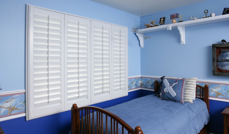 Large plantation shutters covering window in blue kids bedroom in Salt Lake City 